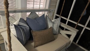 A white wooden swing with a cushioned seat and multiple pillows. - Quaint cottage walk to Historic downtown, restaurants and Silver Comet Trail (Powder Springs)