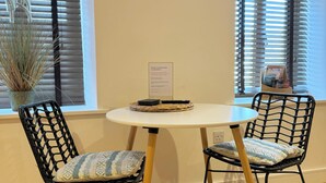 Une pièce comprenant deux fauteuils en osier noir avec des coussins à motifs, une petite table ronde et une plante en pot.