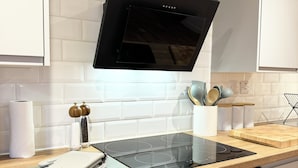 Une cuisine moderne dotée d’une plaque de cuisson à induction noire, d’un four en acier inoxydable et de meubles blancs.