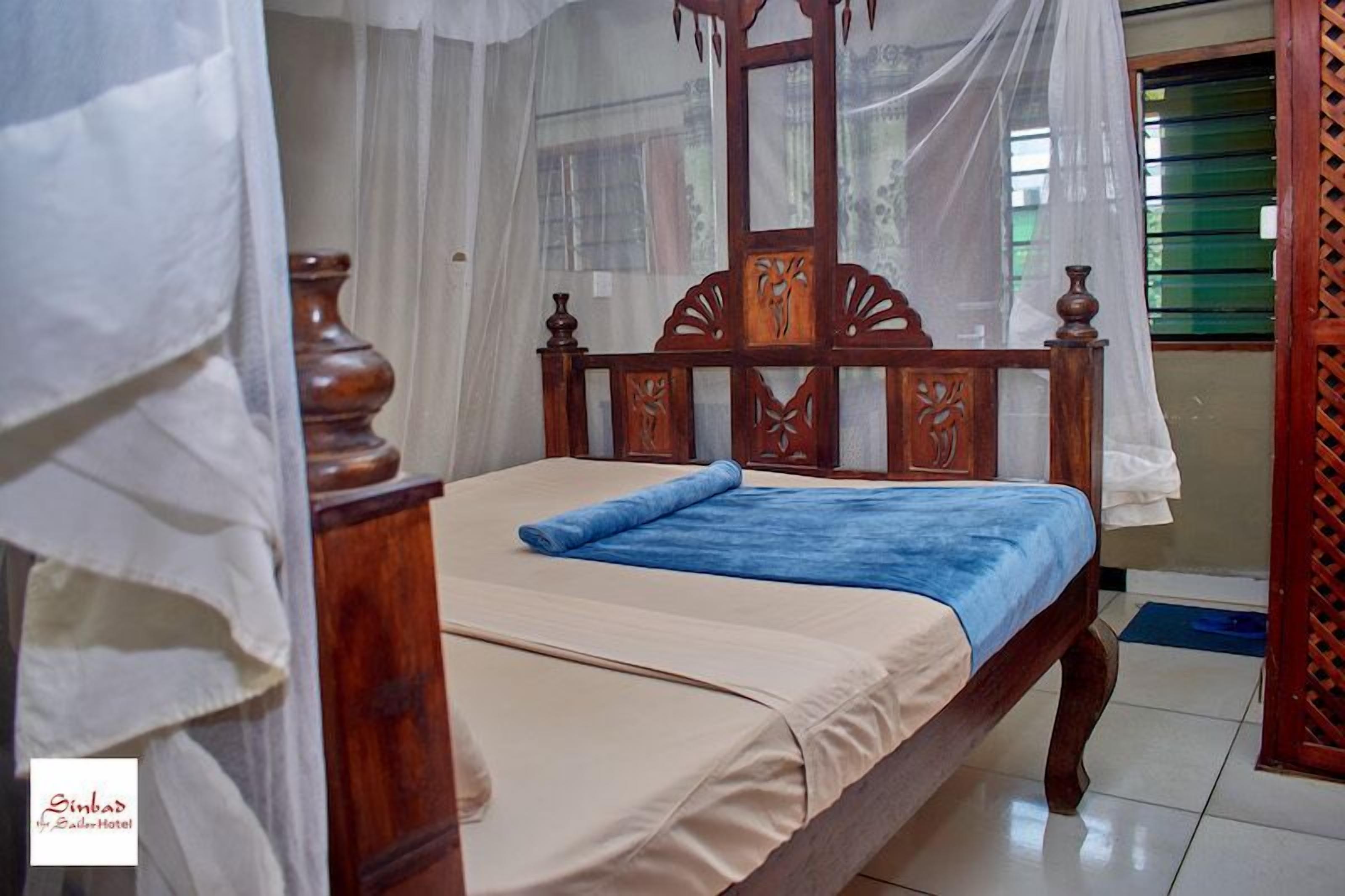 A bed with a wooden headboard, a blue blanket, and a white bedspread.