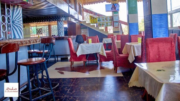 Een restaurant met rode stoelen en tafels, een trap en een kleurrijk ontwerp aan de muur.