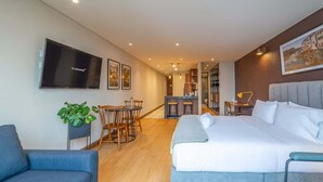 Een moderne hotelkamer met een groot bed, een televisie, een zithoek en een keuken.