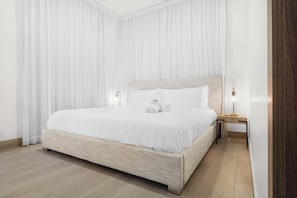 A neatly made bed with white linens, a wooden headboard, and two bedside lamps. - NOK Elegant 3BR Retreat with Private Pool (Punta Cana)