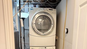 A compact laundry room with two stacked washing machines, a blue detergent bucket, and visible plumbing. - Modern 1BR • Private Entry • Kitchen & W/D (Oshawa)