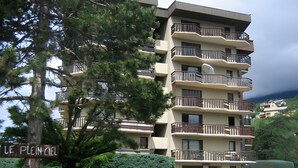 A multi-story building with balconies, a sign reading 'LE PLEIN-CIEL,' and parked cars. - "Aux Aurores" – Charming Apartment with Mountain View and Balcony (Embrun)