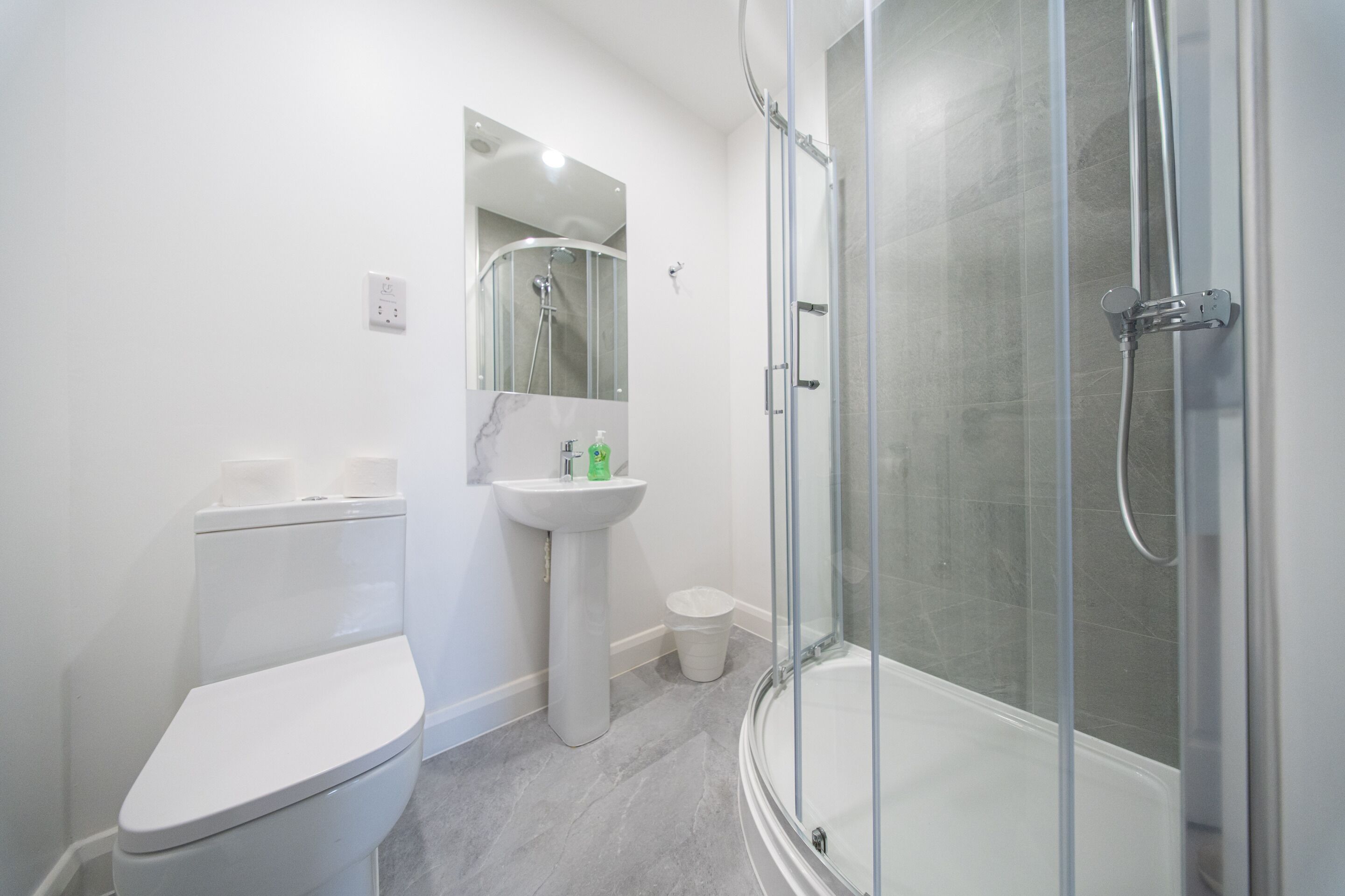 A modern bathroom with a toilet, sink, and glass-enclosed shower.