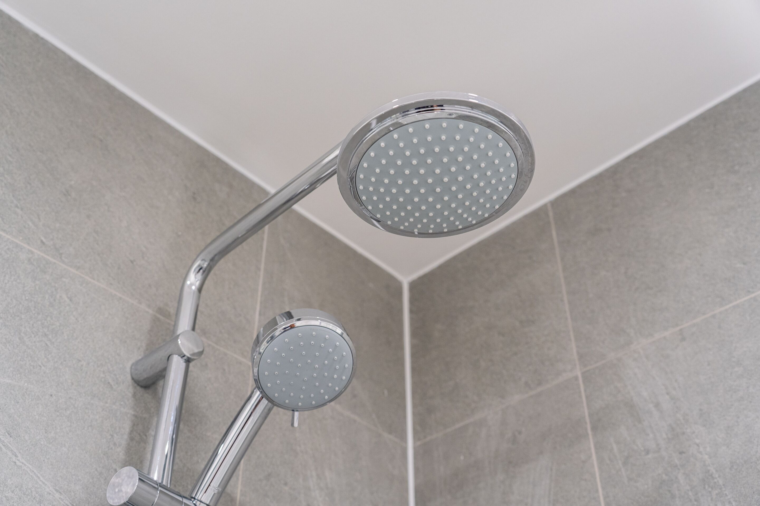 A shower with a handheld attachment and a fixed showerhead.