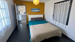 A bedroom with a bed, a hanging light fixture, a window with curtains, and a view of a spiral staircase. - Bright house in the heart of the village-100m from the ocean-6people (Angoulins)