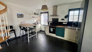 A compact kitchen with a dining area, a built-in oven, and a window providing natural light. - Bright house in the heart of the village-100m from the ocean-6people (Angoulins)