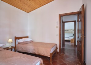 A room with two beds, a wooden ceiling, and a view of a beach through an open door. - Luna Apartment (sleeps 4) (Rivoli veronese)