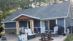 Una casa con porche cubierto, mobiliario exterior y una chimenea.