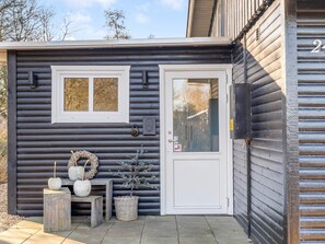 A log cabin with a white door, two windows, and a small porch area with decorative items. - 4 Star Holiday Home in Hemmet (Hemmet)