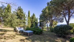 Un jardin avec un banc en bois, une petite table et un matelas posé sur le sol.