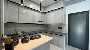A modern kitchen with white cabinets, a marble backsplash, and a built-in oven. - Ahiva Suites Goidhoo (Goidhoo)