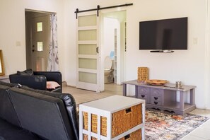 A living room with a sofa, a television, a sliding door, and a small table with a basket.