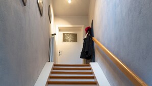 En trappa med trästeg och ett vitt handledare, som leder upp till en dörr med en lampa ovanför.