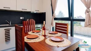 A dining area with a wooden table set for four, a bottle of wine, and two glasses.
