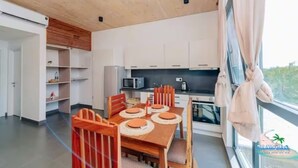 A modern kitchen with white cabinets, a microwave, and a stove. There is a dining area with a wooden table and chairs.