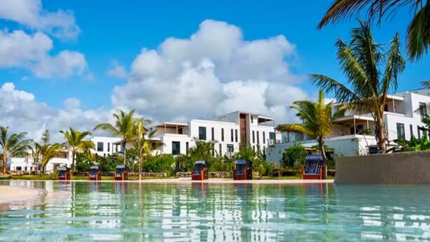 A resort with a swimming pool, palm trees, and modern buildings.