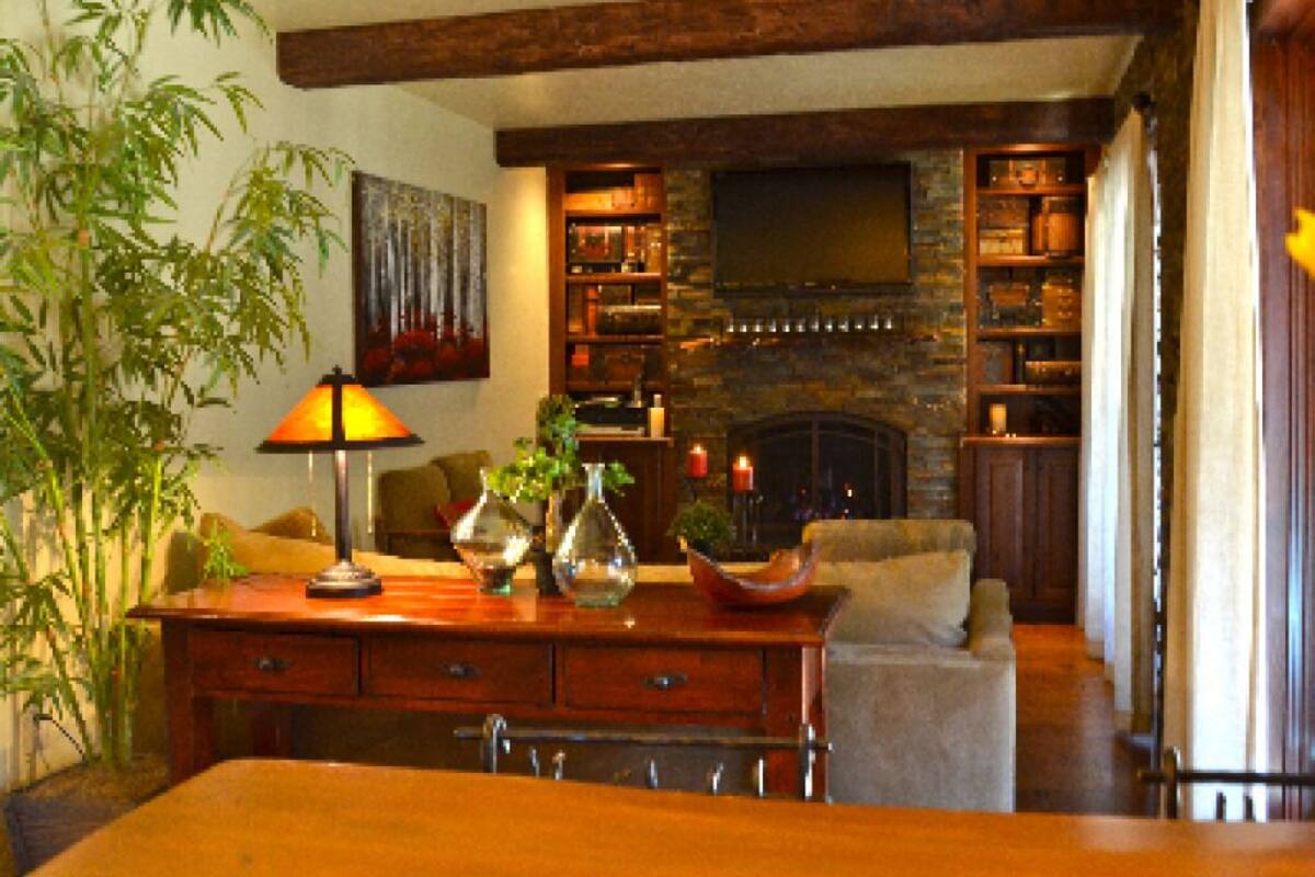 Una sala de estar acogedora con chimenea, vigas de madera, televisor y estantería.