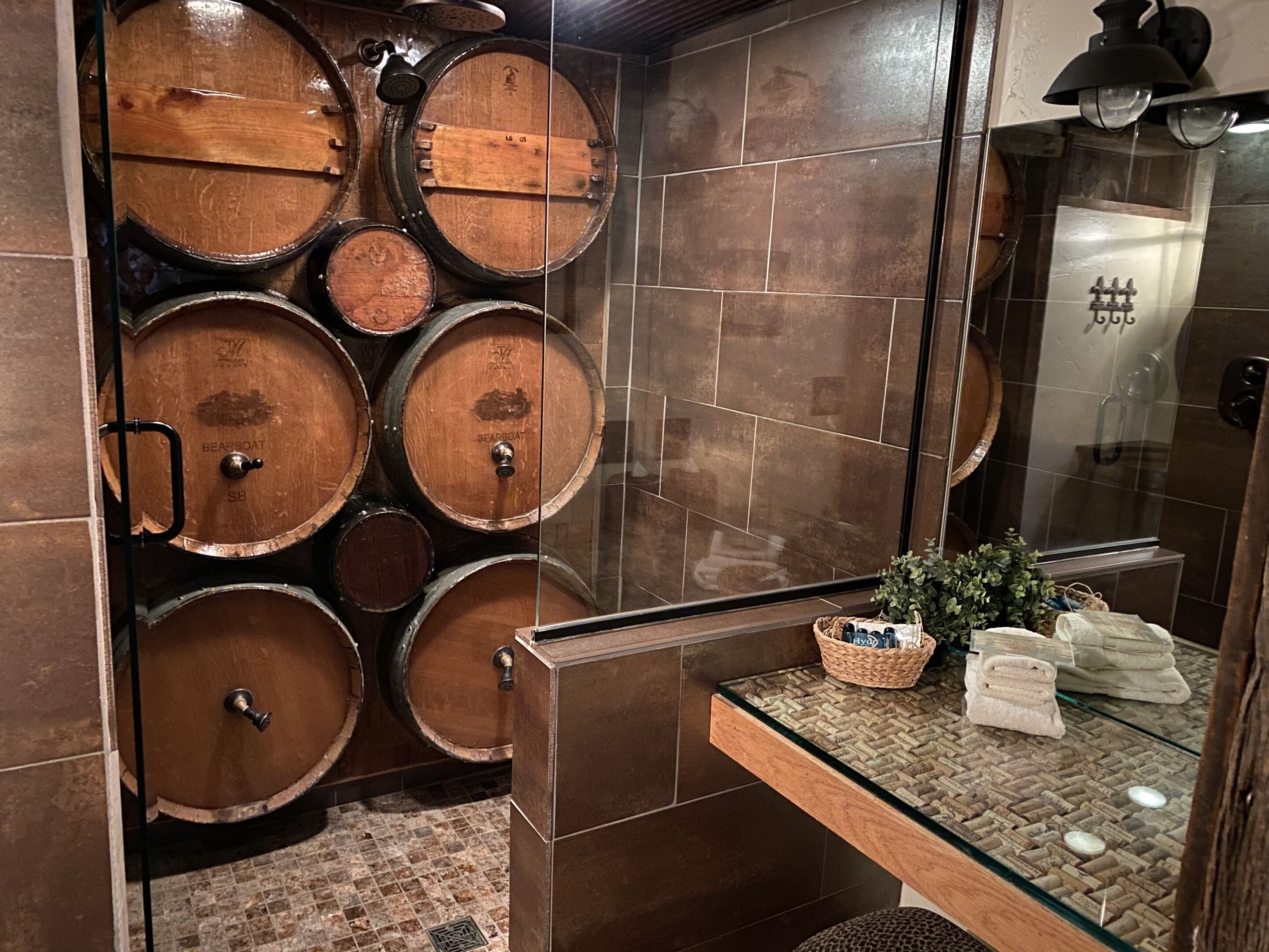 Ein Badezimmer mit Holzfässern, einer Glasdusche und einem Handtuchhalter.