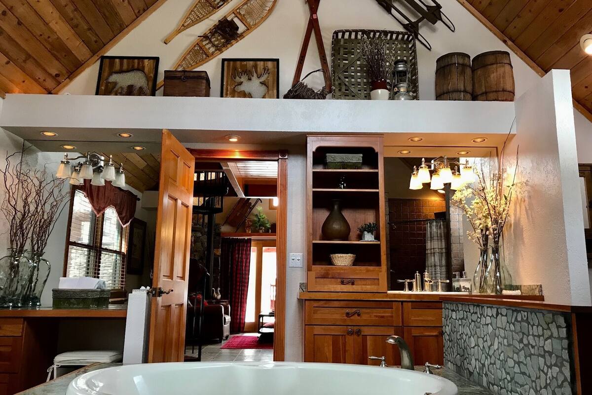 Un baño espacioso con una bañera grande, armarios de madera y una pared de acento de piedra.
