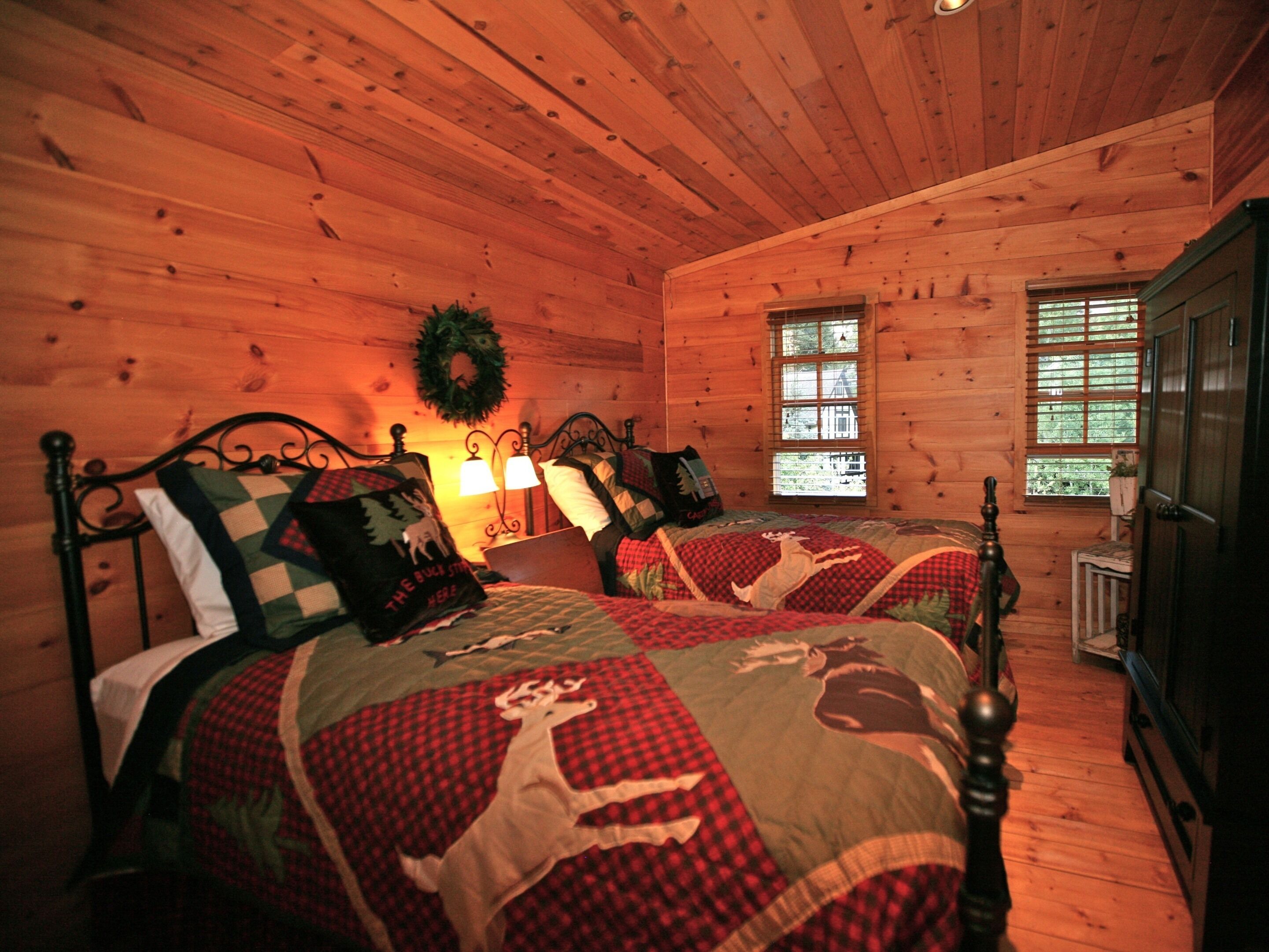 Quarto de cabana acolhedor com duas camas, paredes de madeira, uma janela e uma porta.