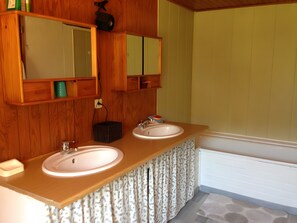 Ein Badezimmer mit Holzschränken, zwei Waschbecken, einem Spiegel und einer Heizung.