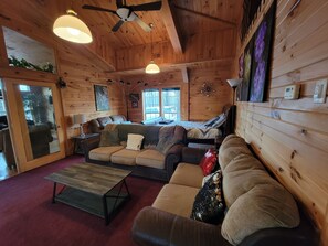 Ein gemütliches Blockhaus-Interieur mit Holzwänden, einer Couch, einem Couchtisch und einem Deckenventilator.