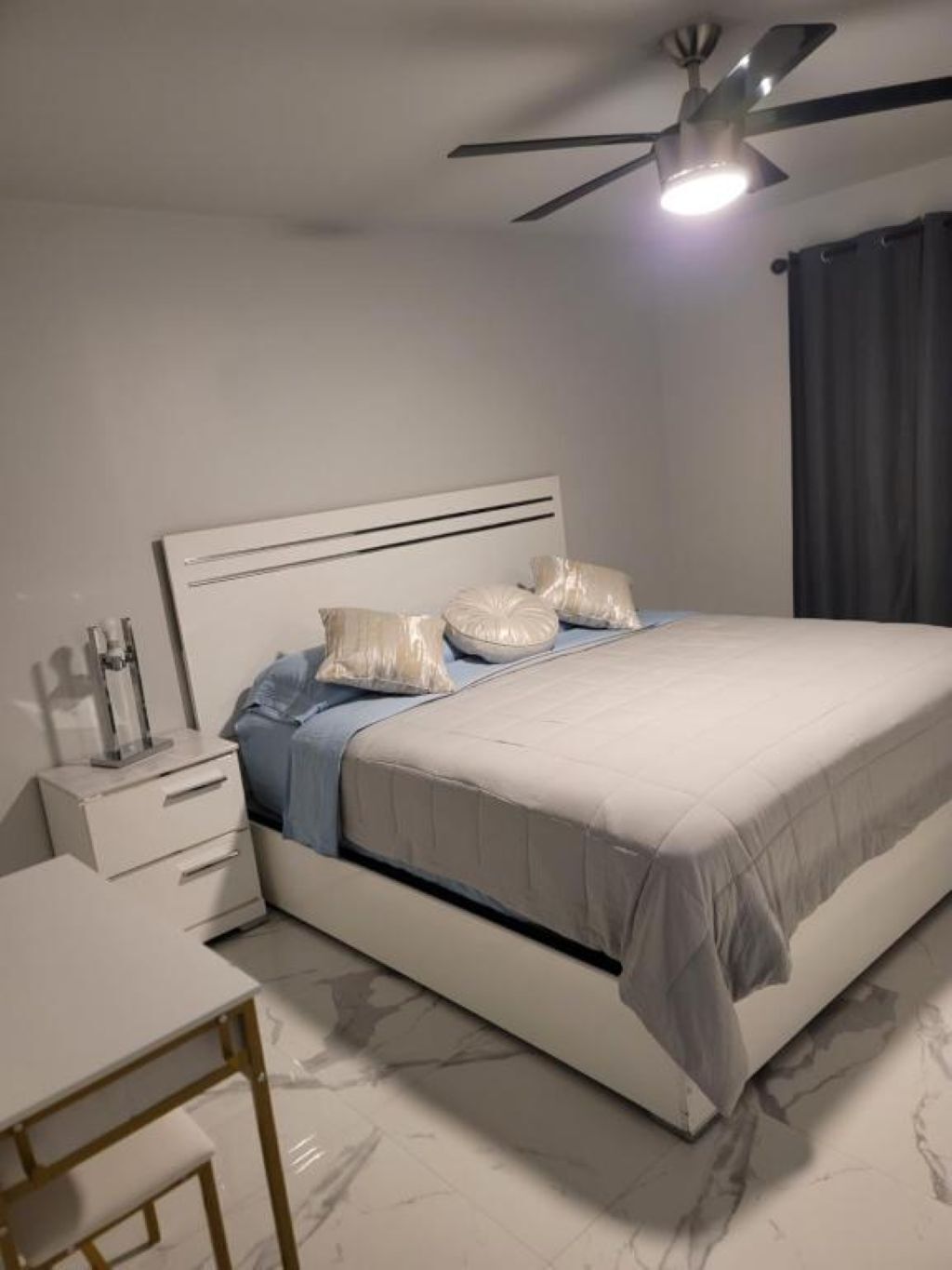 A modern bedroom with a bed, bedside table, and a desk.