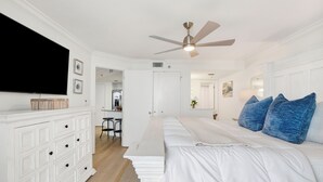 A bedroom with a bed, white dresser, ceiling fan, and a TV on the wall. - Island Pass OB • Steps to Beach • In the Heart of OB • Fully Loaded • Bunk Room (Orange Beach)
