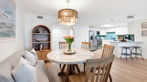 A modern kitchen with white cabinets, a central island, and a dining area with a round table and chairs. - Island Pass OB • Steps to Beach • In the Heart of OB • Fully Loaded • Bunk Room (Orange Beach)