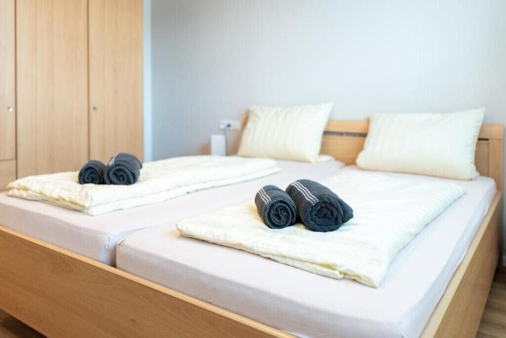 Una cama doble con dos almohadas y toallas enrolladas a cada lado.