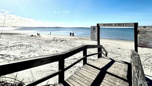 Ein Holzsteg führt zu einem Strand, an dem ein Schild 'BYERS STREET' zeigt.