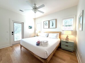 A hotel room with a bed, a ceiling fan, a nightstand, a lamp, and a window with blinds. - Gypsy Mariner  - Tybee Is. Private Spa, Shuffleboard, 3 Kings, 1 Queen Sleeper (Tybee Island)