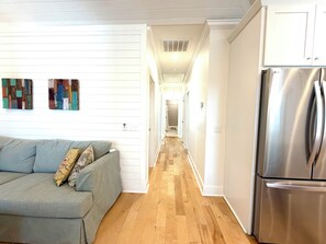 A modern kitchen with a stainless steel refrigerator, a wooden floor, and a grey sofa with floral cushions. - Gypsy Mariner  - Tybee Is. Private Spa, Shuffleboard, 3 Kings, 1 Queen Sleeper (Tybee Island)