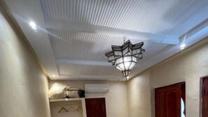 Habitació d'hotel amb un llit, una cadira, un armari i un lluminari al sostre.
