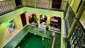 Un pati interior amb una piscina central, passadissos en arc i una zona de seients amb cadires i taules.