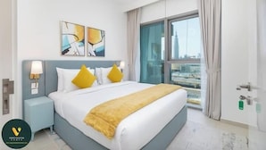 A modern hotel room with a large bed, a nightstand, a city view through the window, and abstract wall art. - Vogue | Downtown with Direct Access to Dubai Mall (Dubai)