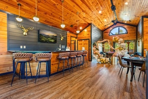 A rustic wooden interior with a bar area featuring leather barstools and pendant lighting. - Sleeps 30: Amazing Views! Perfect for Groups! (Gatlinburg)