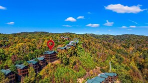 A row of wooden cabins with green roofs, surrounded by dense forest, and a red location marker. - Sleeps 30: Amazing Views! Perfect for Groups! (Gatlinburg)
