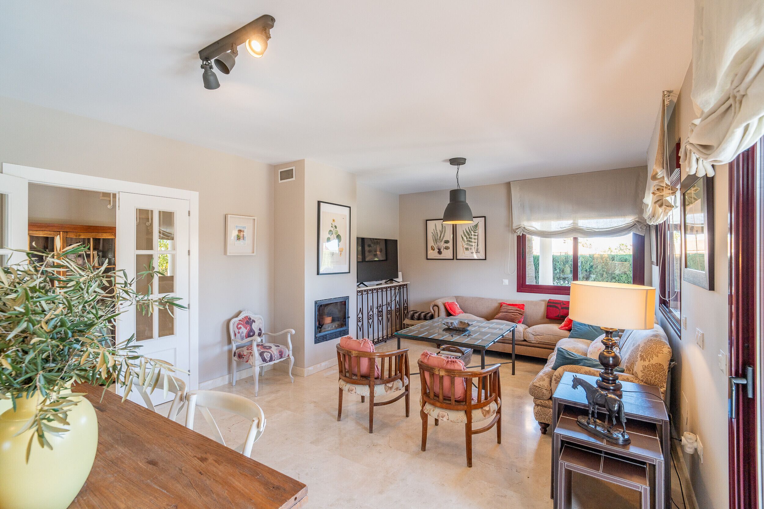 Amplia sala de estar con chimenea, comedor con mesa de madera y sofá con lámpara.