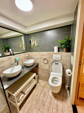 A modern bathroom with two sinks, a toilet, a mirror, and a towel rack. - A&A Patio Suite (Amsterdam)
