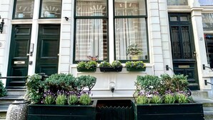 Une maison de ville avec une porte d’entrée noire, des fenêtres à cadre blanc et une façade en briques.
