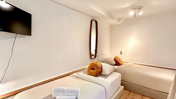 A modern bedroom with a bed, a sofa, a TV mounted on the wall, and a mirror. - A&A Patio Suite (Amsterdam)