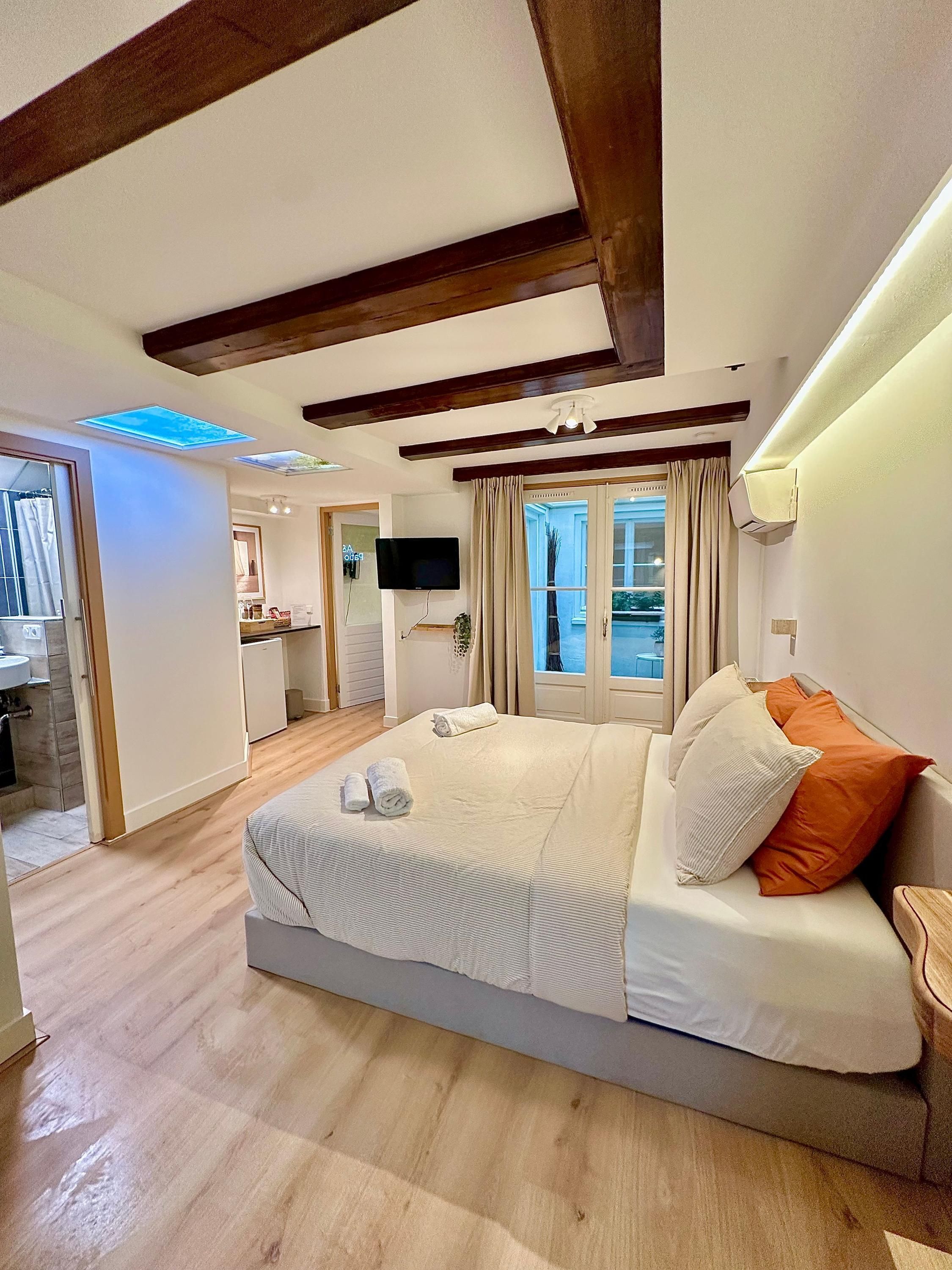 A bedroom with a bed, a TV, and a view of the outside.