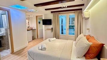 A bedroom with a bed, a TV, and a view of the outside.