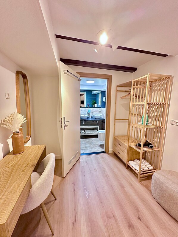 A modern bedroom with a wooden desk, a mirror, a wardrobe, and a view into the bathroom. - A&A Patio Suite (Amsterdam)