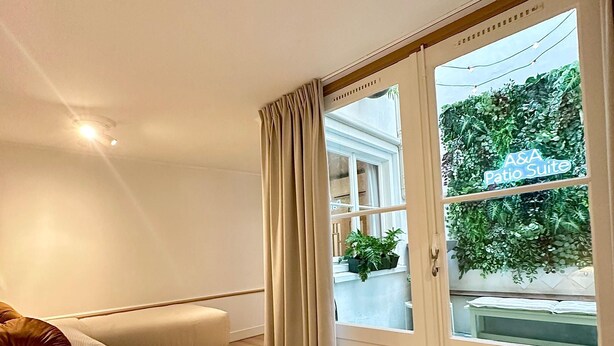Une chambre d’hôtel avec un lit, une fenêtre avec des rideaux et une vue sur la verdure environnante.