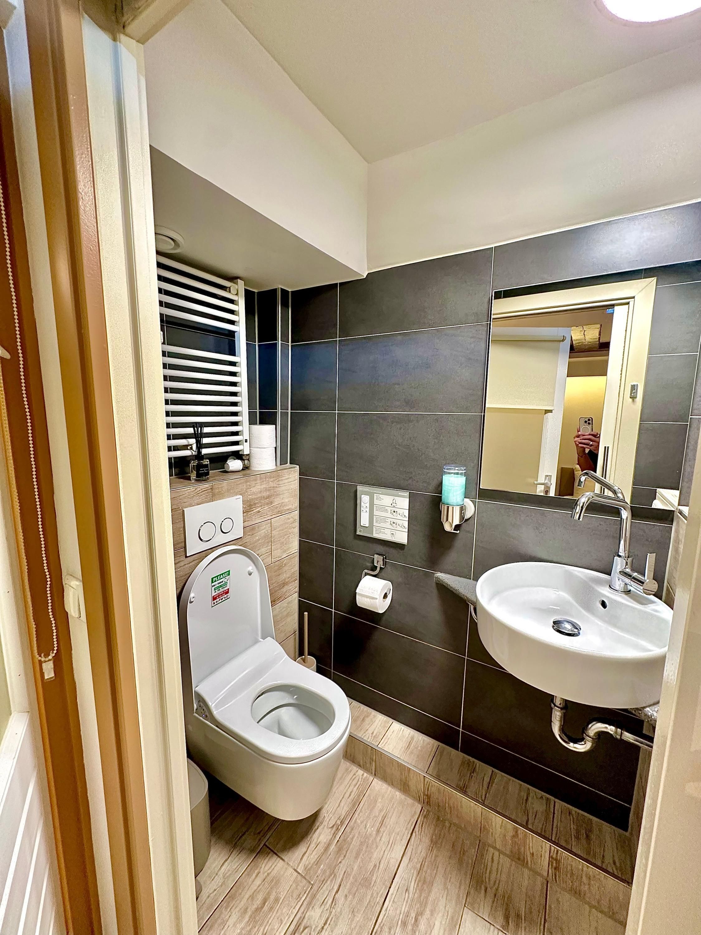 Un baño moderno con inodoro, lavamanos y espejo.